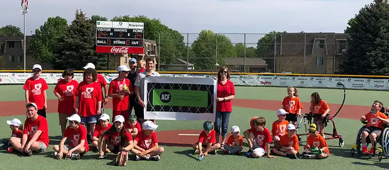 Players hold up an Ankeny Community Foundation sign at Ankeny Miracle Park